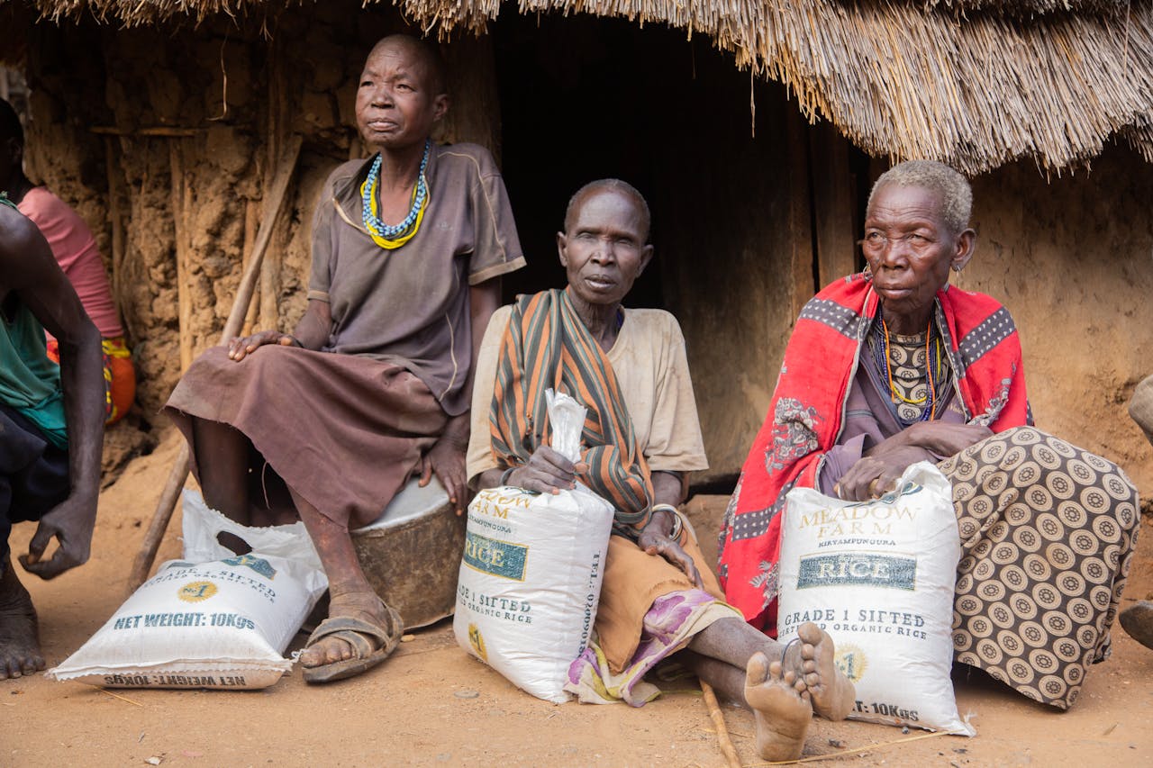 about-01 African women seated with rice aid packages in a rural setting demonstrating aid distribution.